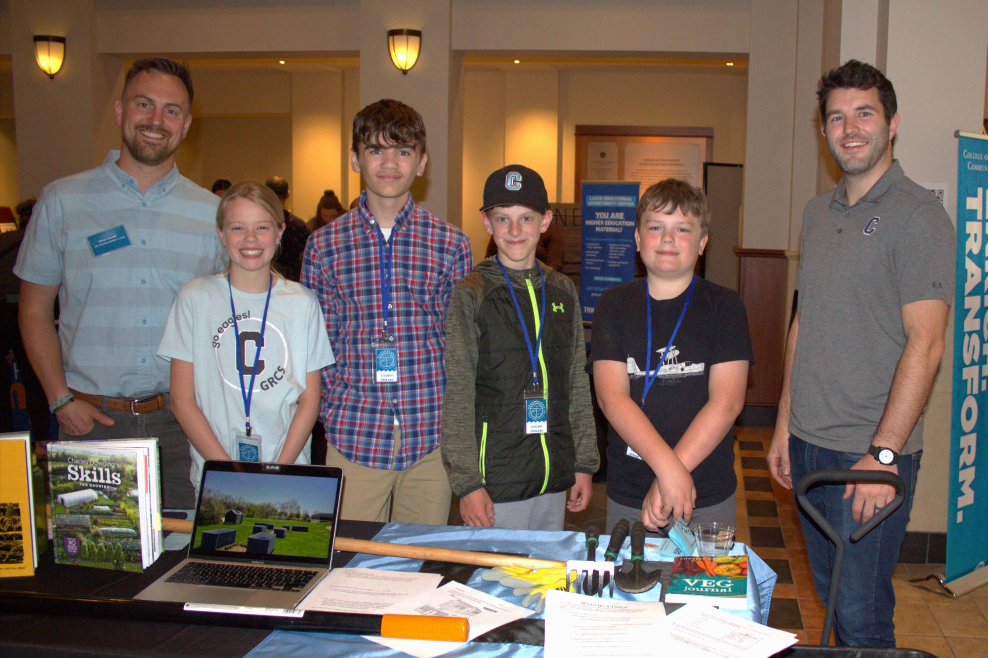 Two teachers and students at their Groundswell table at the student project showcase